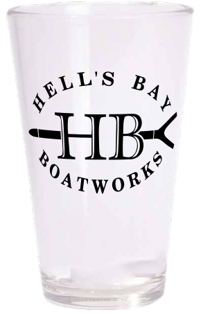A clear glass drinking tumbler with a black printed logo reading 'HELL'S BAY BOATWORKS' and a large 'HB' with crossed tools, shown on a plain white background.